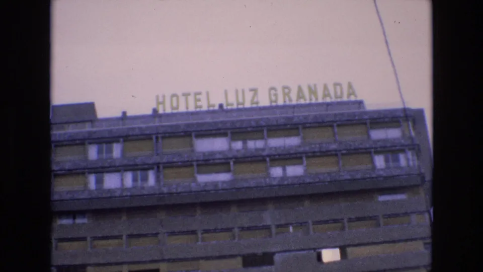 1972 Spain home-movie frame showing the HOTEL LUZ GRANADA rooftop sign, pale sky, and upper window rows of the hotel facade.