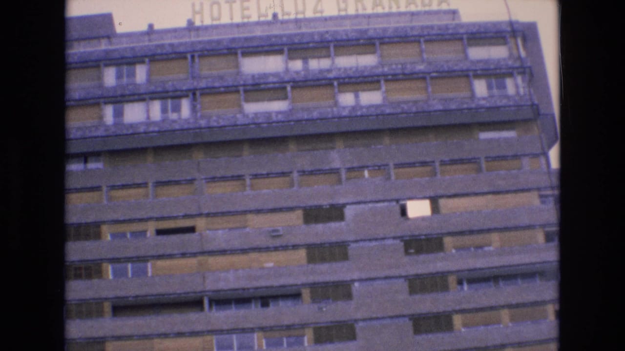 1972 Spain home-movie frame showing the upper stories of Hotel Luz Granada with repeated balconies, shuttered windows, and partial rooftop lettering.