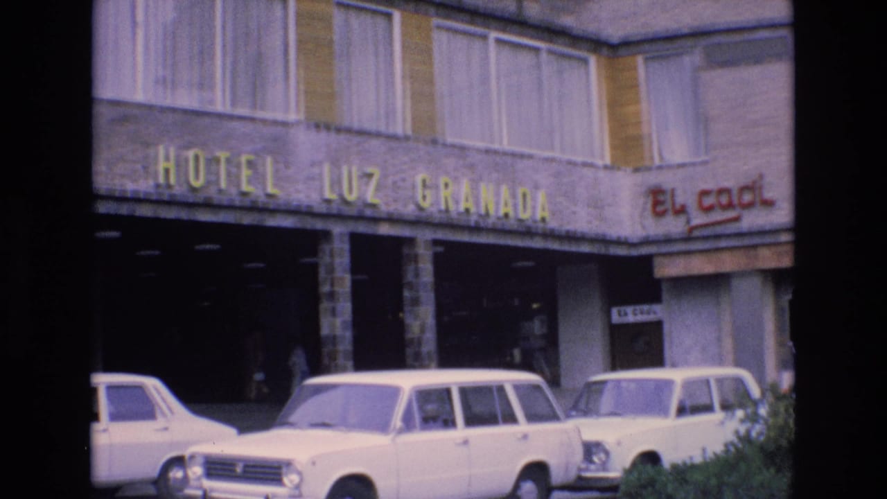 1972 Spain hotel frontage showing the yellow Hotel Luz Granada sign above parked white sedans and a station wagon, with El Cacil signage on the right.