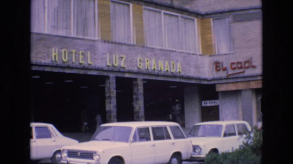 1972 Spain hotel frontage showing the yellow Hotel Luz Granada sign above parked white sedans and a station wagon, with El Cacil signage on the right.