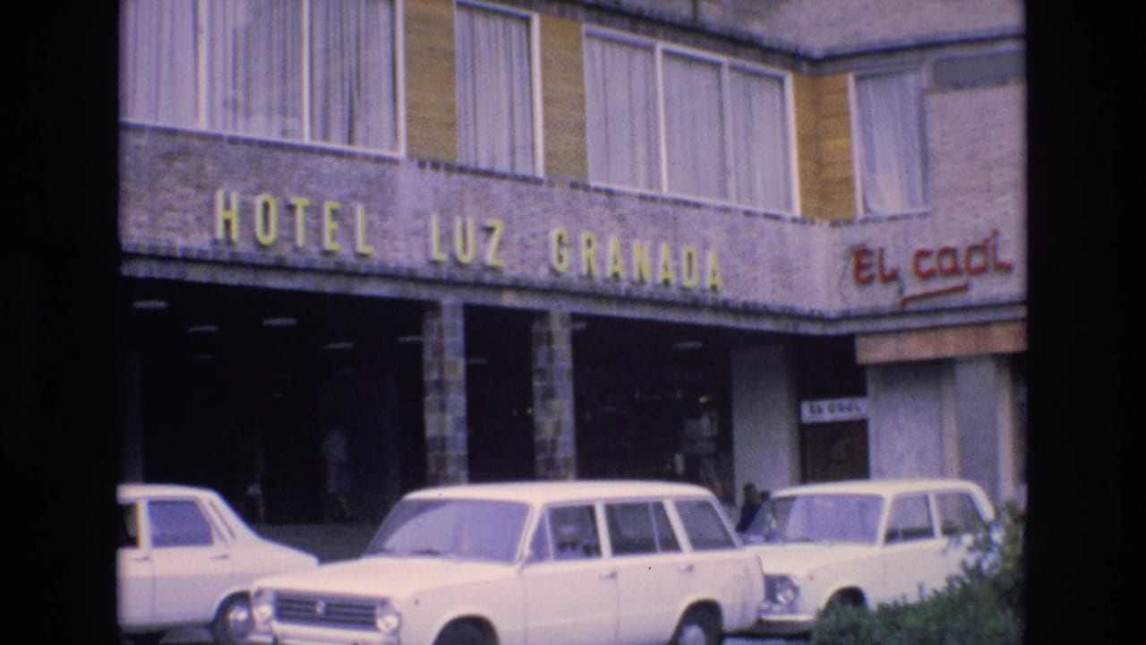 Hotel Luz Granada sign above a row of white cars parked in front of the entrance.