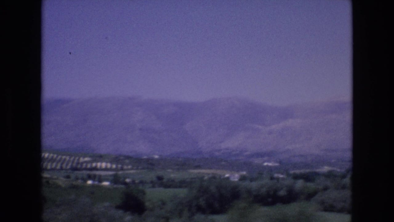 1972 Spain 8mm frame looking across a hazy mountain range and green valley from an elevated rural viewpoint.