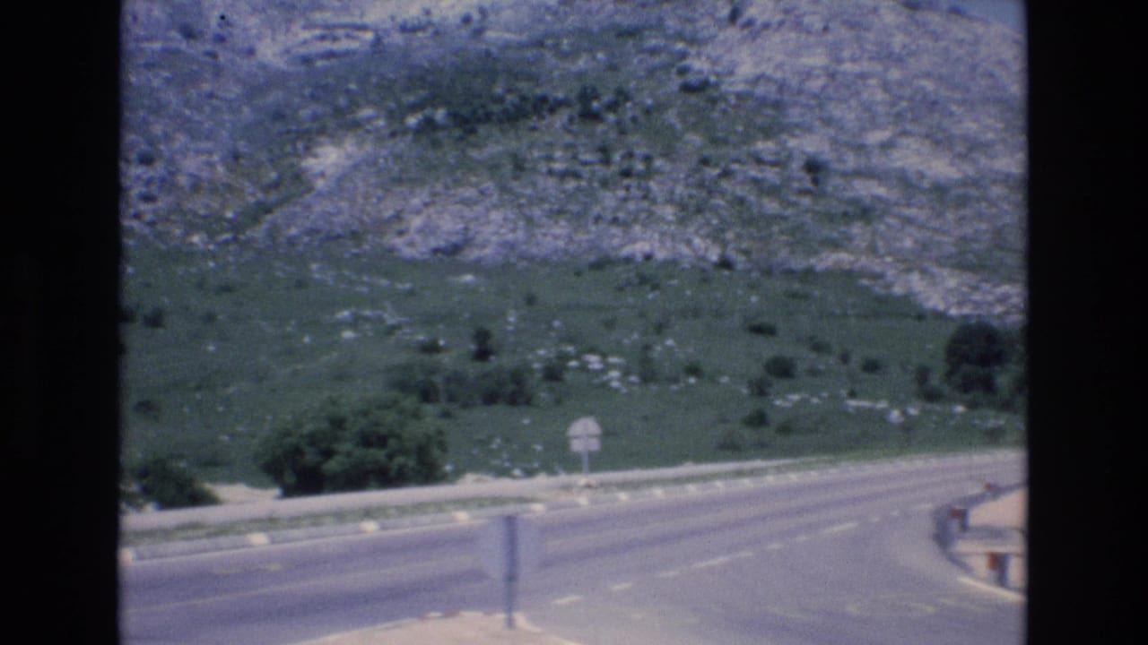 Curving mountain road with rocky hillside beyond.