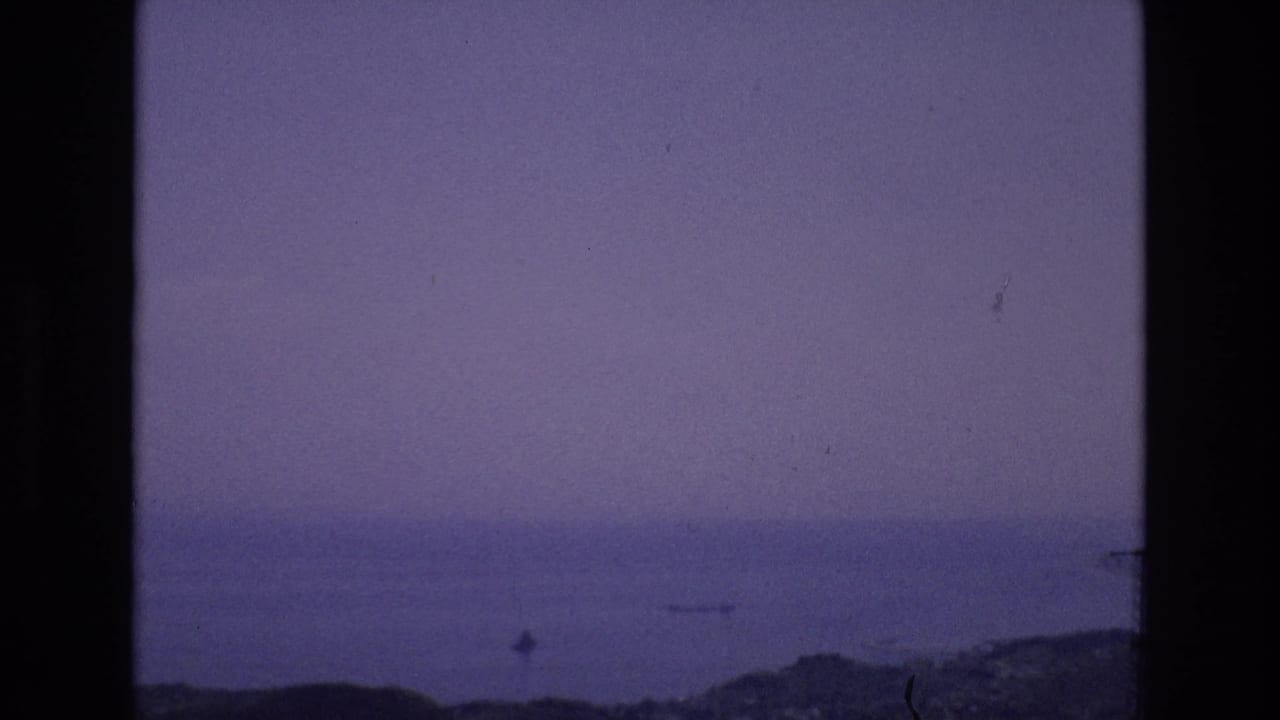 Hazy water view with shoreline and dark vertical film border.
