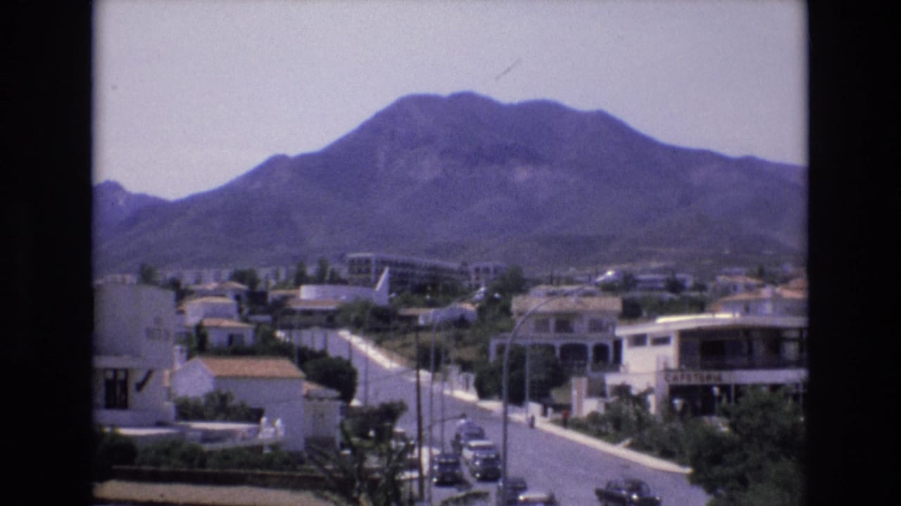 Residential street and white buildings with a mountain filling the background.