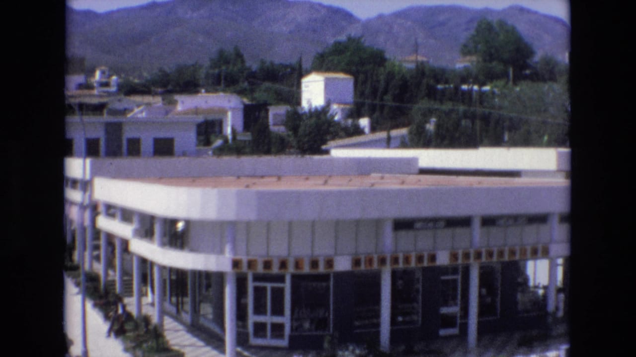 White building and greenery seen from an elevated street view.