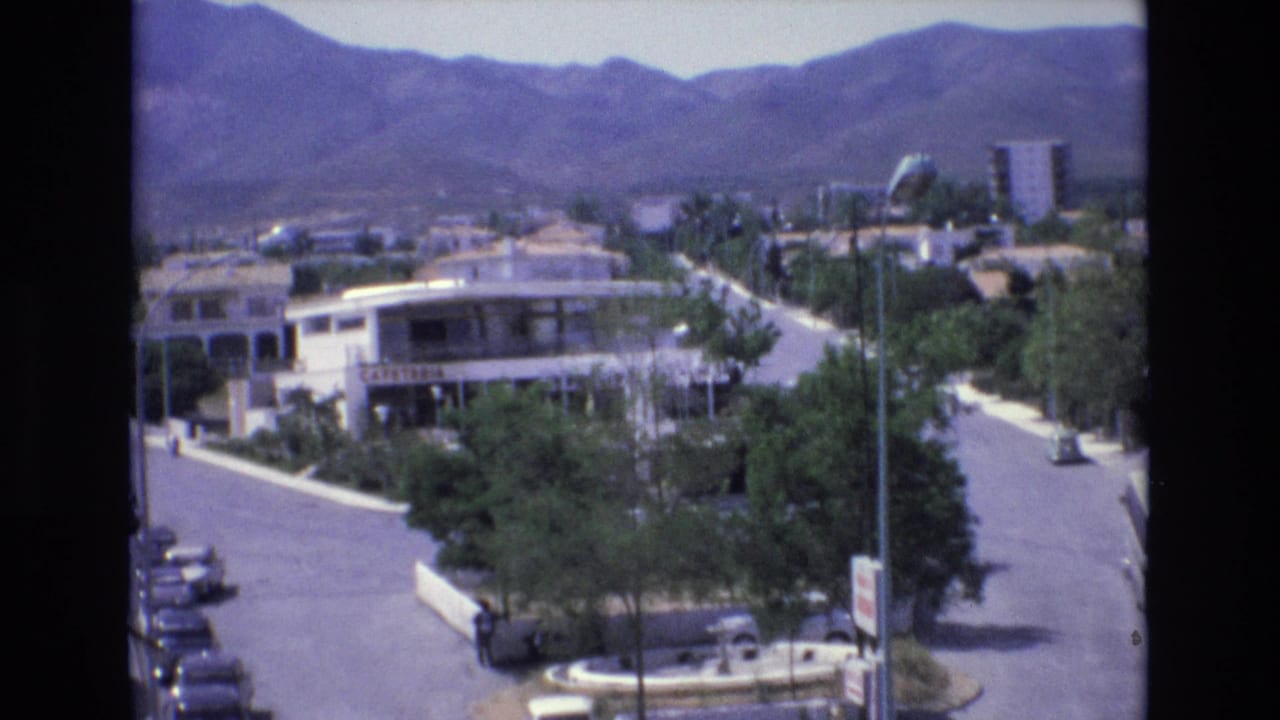Similar elevated street view with cars, trees, buildings, and mountains behind the resort area.