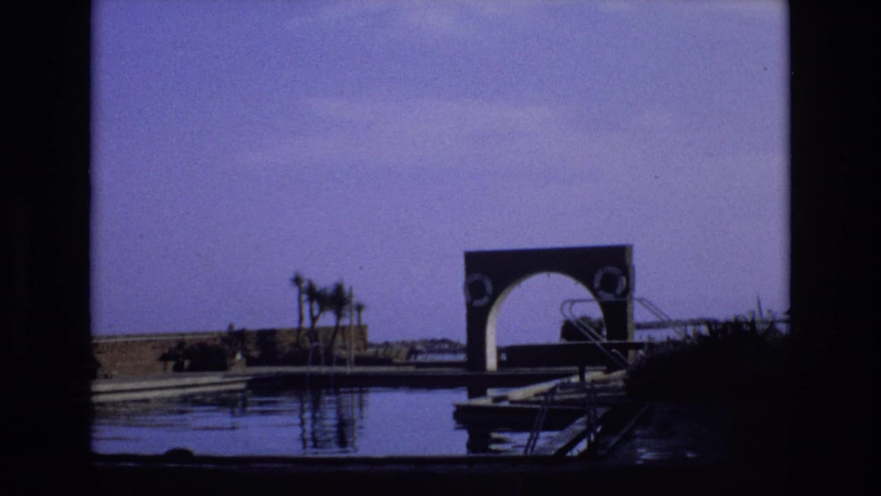 A similar waterfront view shows the arched structure, dock, palms, and still water.