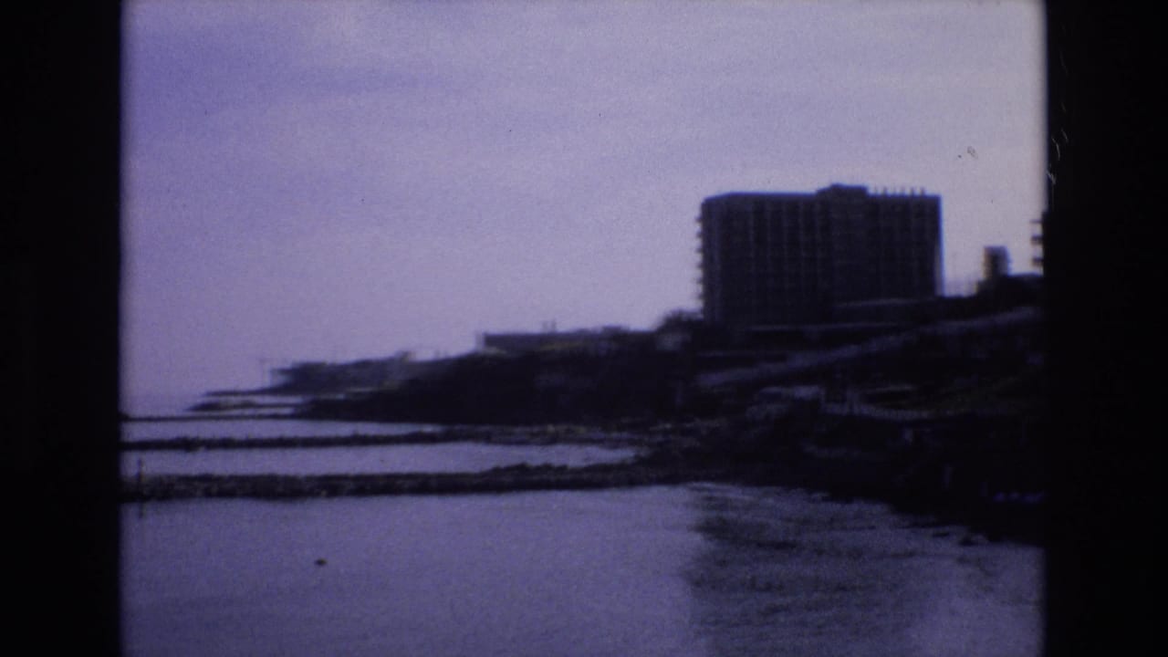 Distant high-rise building beside a bay and dark shoreline.