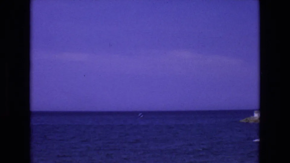 A 1972 Spain coastal view shows deep blue Mediterranean water, a level horizon, pale sky, and a small distant boat near the right side of the frame.