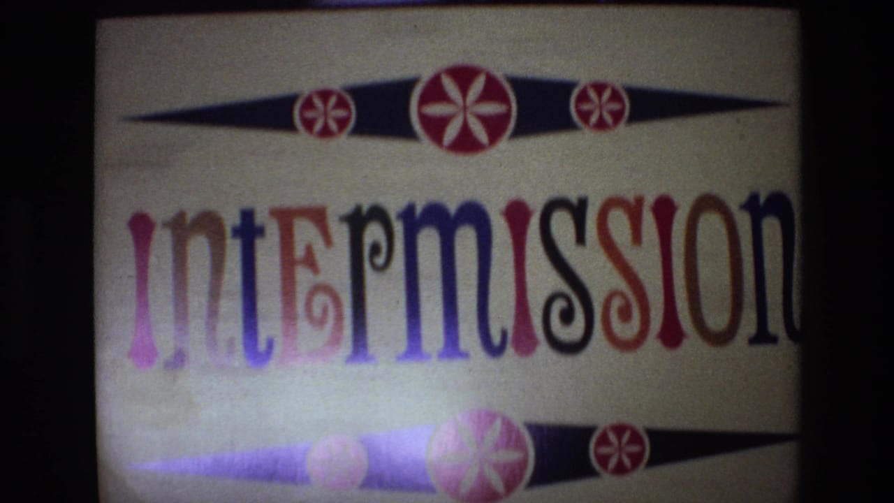 Intermission title card projected on a screen with ornate colored letters.