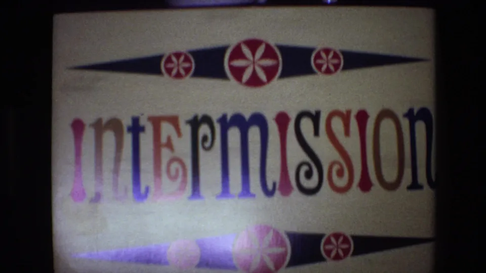 1972 Spain 8mm frame showing the intermission title card lower in the projected view, with large multicolored lettering, a bottom decorative band, and visible film grain.