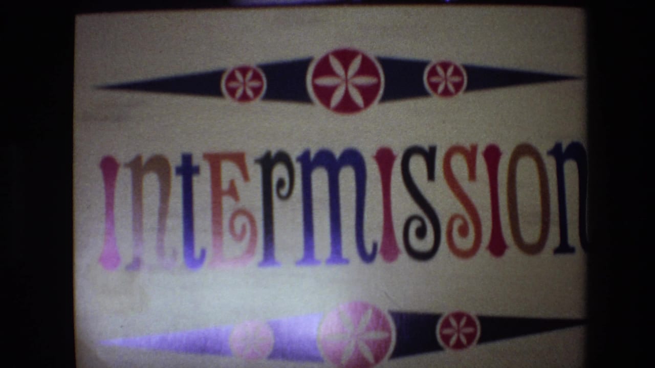 1972 Spain 8mm frame showing a decorative intermission title card with multicolored letters, cream background, and red starburst ornaments.
