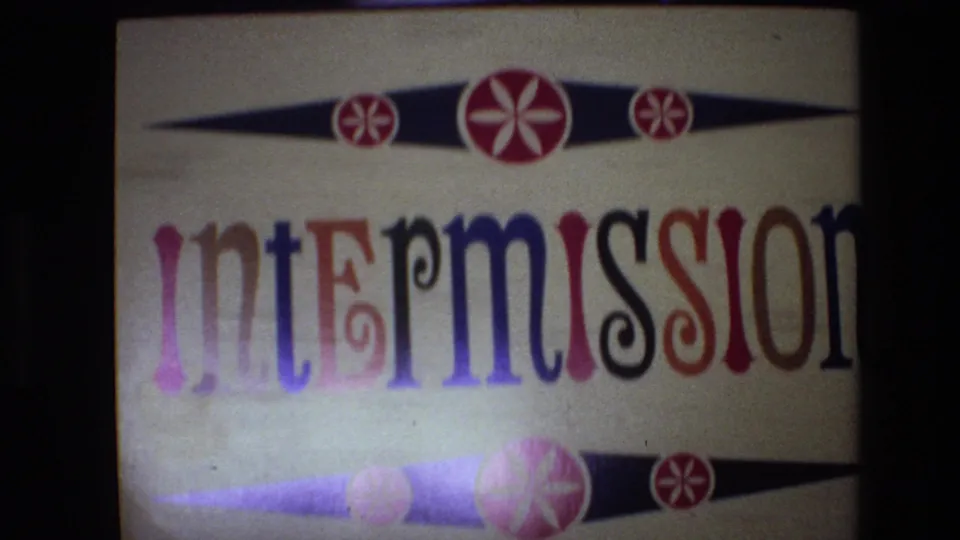 1972 Spain 8mm frame of the repeated intermission card, showing multicolored lettering, decorative red circles, and dark film edges.