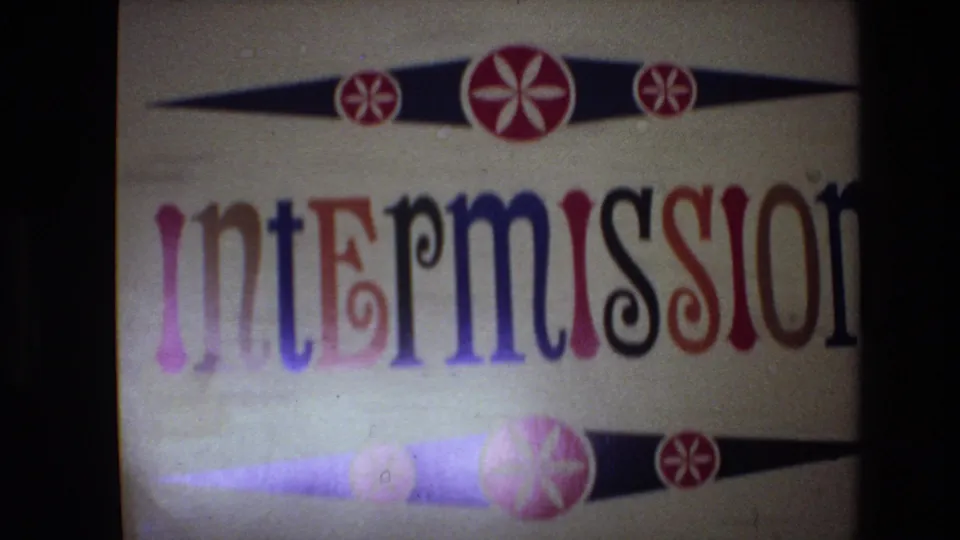 Spain 1972 8mm frame showing the static intermission card at the end of the clip, with colorful lettering, red circular motifs, and visible analog grain and color bleed.