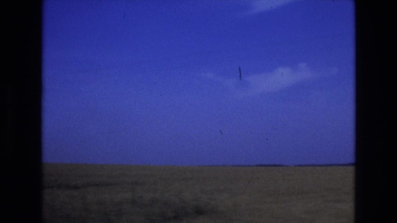 Open field horizon under a blue sky with a small white cloud.