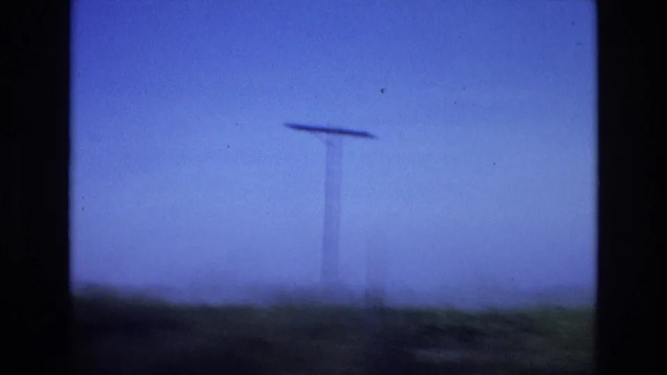 1972 Spain 8mm frame showing a blurred telephone pole and low rural horizon, with vehicle motion softening the roadside view.