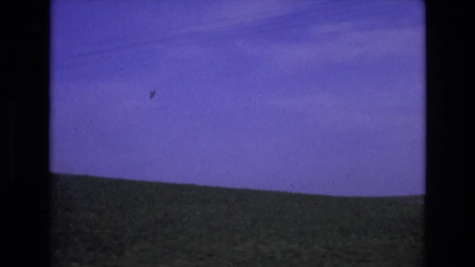 Metadata-supported 1972 Spain home-movie frame showing an open green hillside beneath a blue sky, with visible 8mm gate borders and color shift.