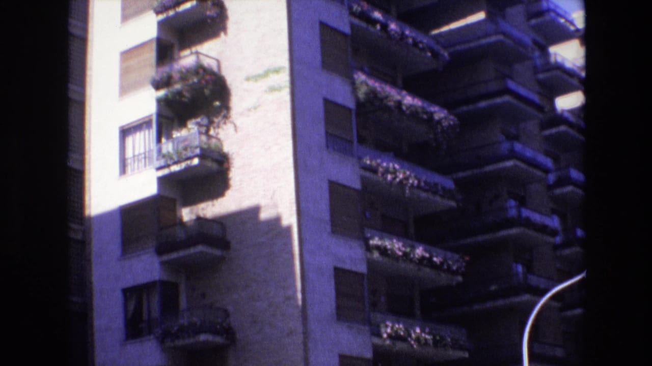 Apartment balconies and windows divided by a dark film-frame border.