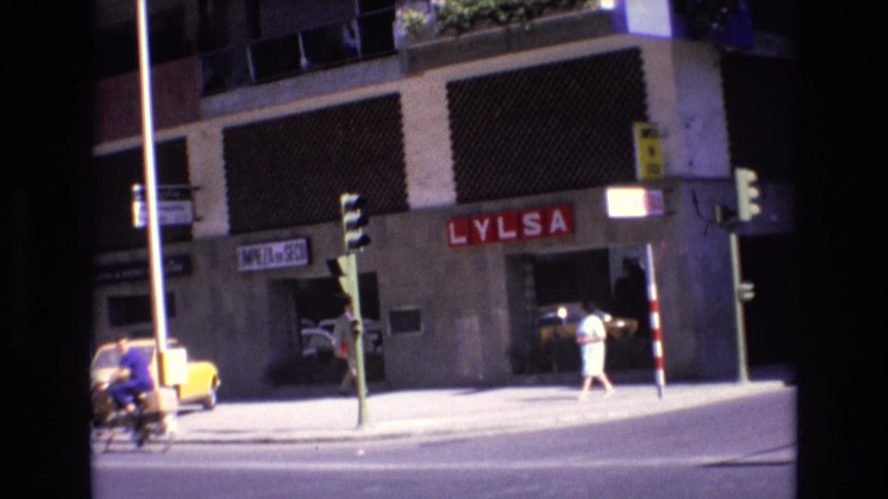 Street corner with LYLSA sign, traffic lights, cyclist, pedestrian, and building facade.