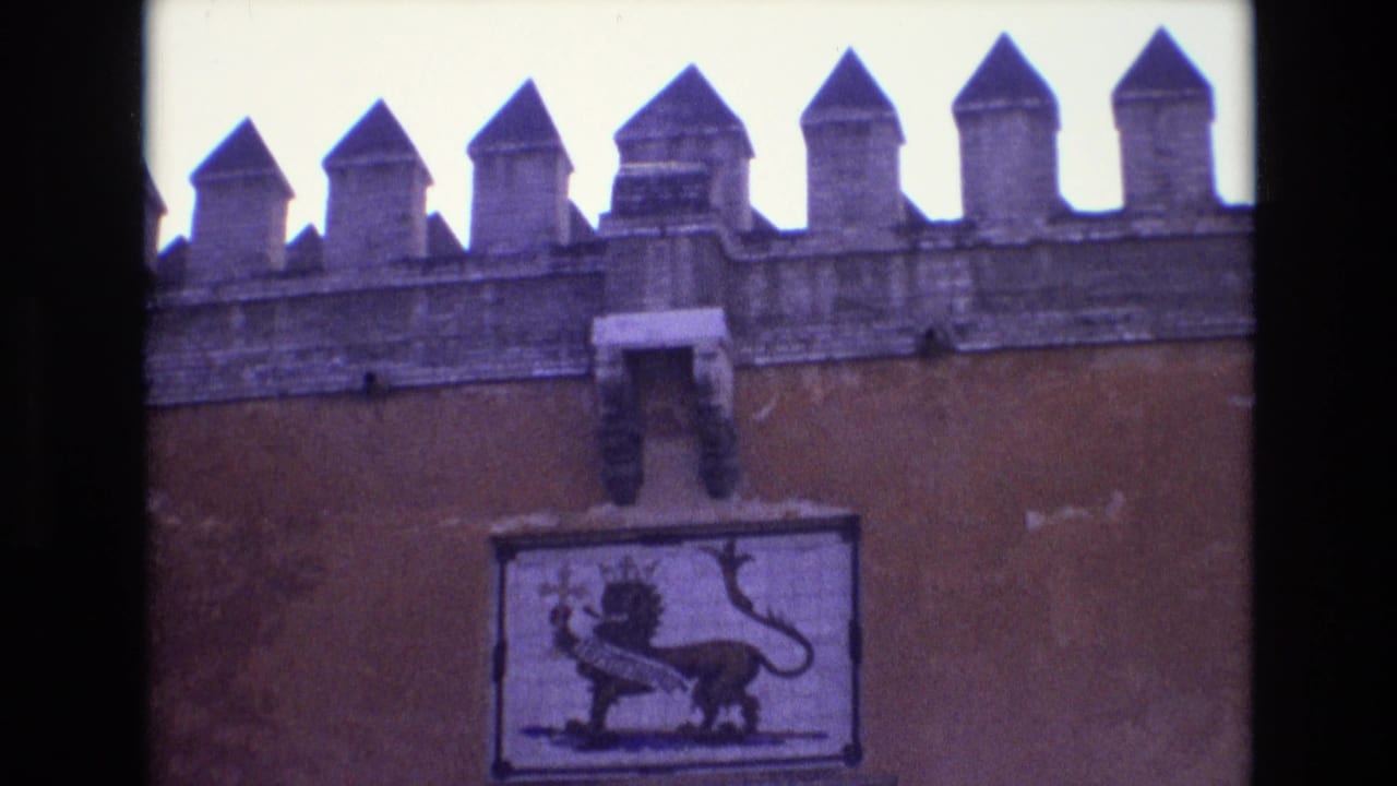 1972 Spain 8mm frame showing a crenellated historic wall and a crowned lion symbol panel above the upper part of a stone entrance.