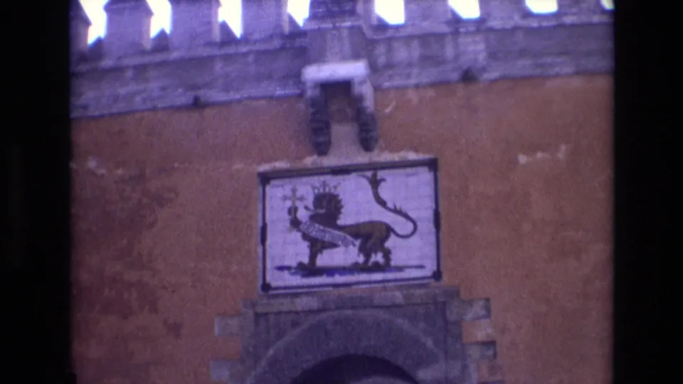 1972 Spain 8mm frame with a crowned lion emblem panel above a rounded stone arch set into a weathered ochre wall.