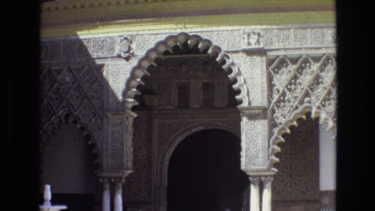 1972 Spain home-movie frame showing an ornate scalloped archway, carved stone facade, columns, and geometric decoration in strong sunlight.