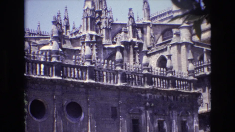 1972 Spain 8mm frame showing an ornate cathedral facade with pointed spires, stone balustrade, circular windows, and projected-film borders.