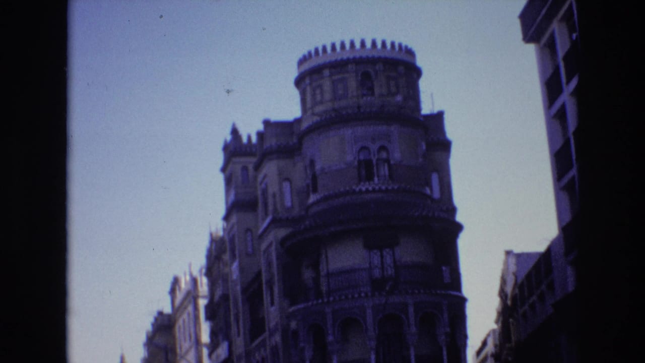 Ornate rounded corner building with balconies and arched windows under a clear sky.