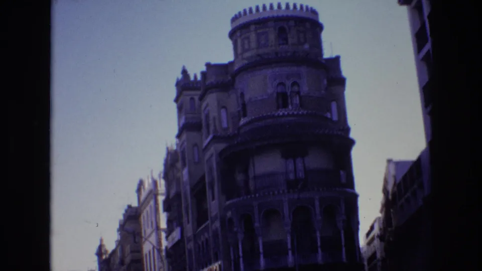 The frame shows a low-angle 1972 Spain city view of a cylindrical corner tower, decorative roofline, balconies, and adjacent buildings.