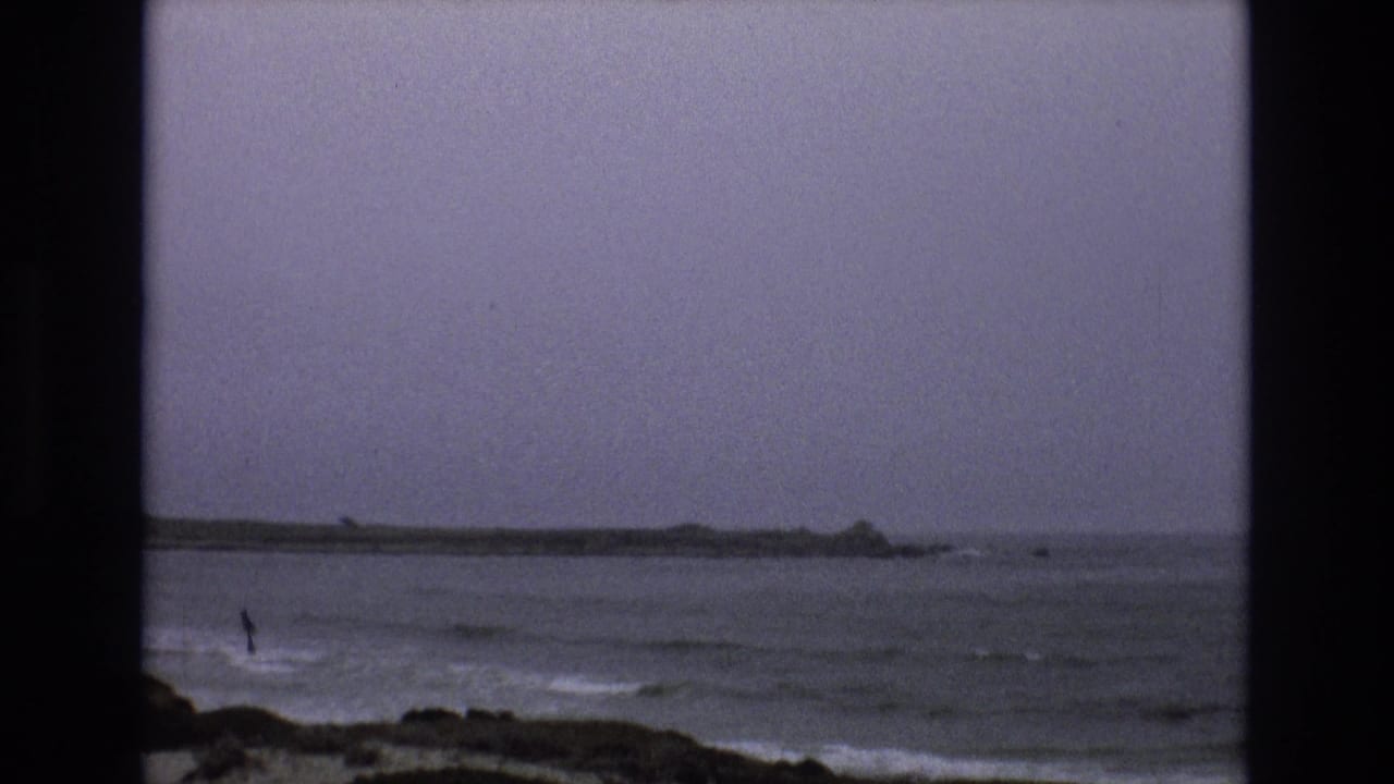 Dark shoreline and choppy water sit under a heavy gray sky.