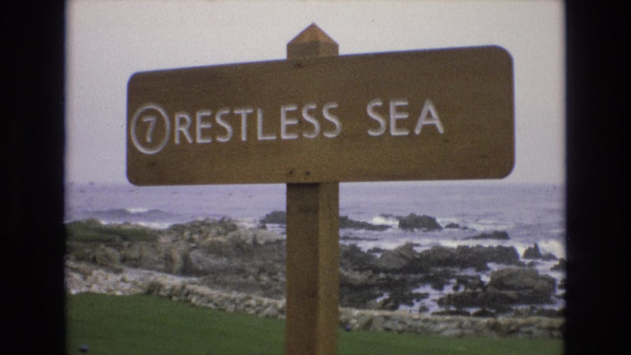 Wooden sign reading "7 RESTLESS SEA" in front of a rocky ocean shoreline.