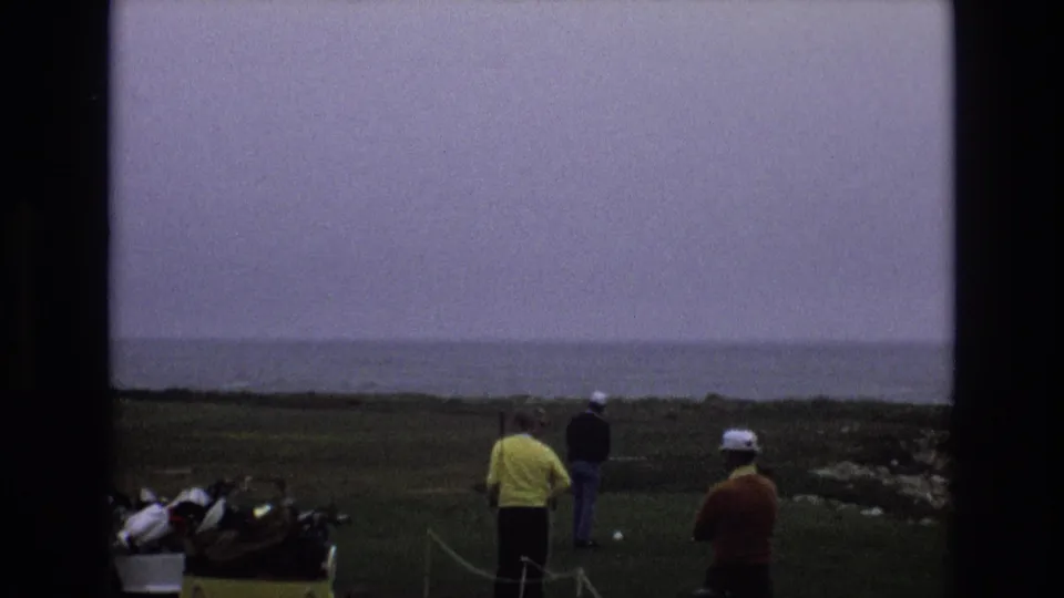 The final 1973 8mm frame shows men in casual clothing on a coastal golf course, including a yellow shirt and white cap, with golf bags at left and the sea beyond.