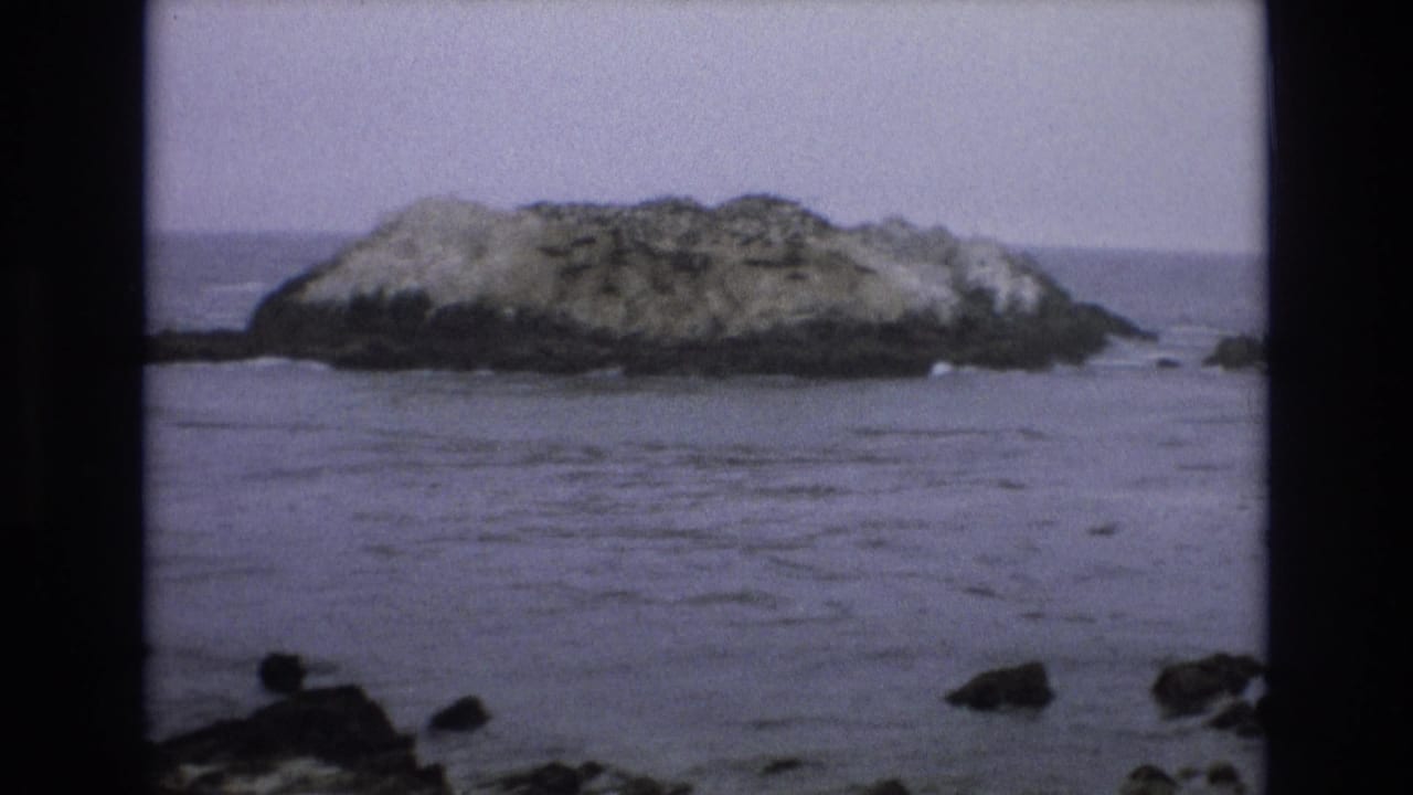 Small rocky island surrounded by calm ocean water.