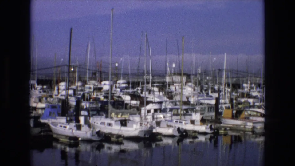 1973 Central Coast California 8mm frame showing a marina crowded with sailboats, small motor vessels, dock structures, and quiet reflective water.
