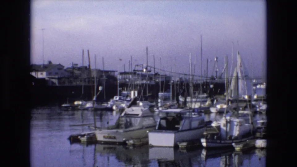 1973 Central Coast California marina view with moored recreational boats, a cluster of mast lines, calm water, and soft faded 8mm color.