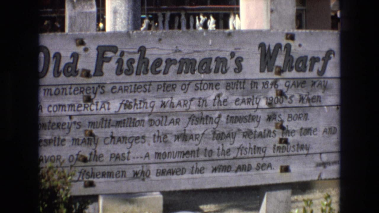 Second 1973 8mm view of the weathered Old Fisherman's Wharf sign, with the same painted historical wording and waterfront structure details visible.