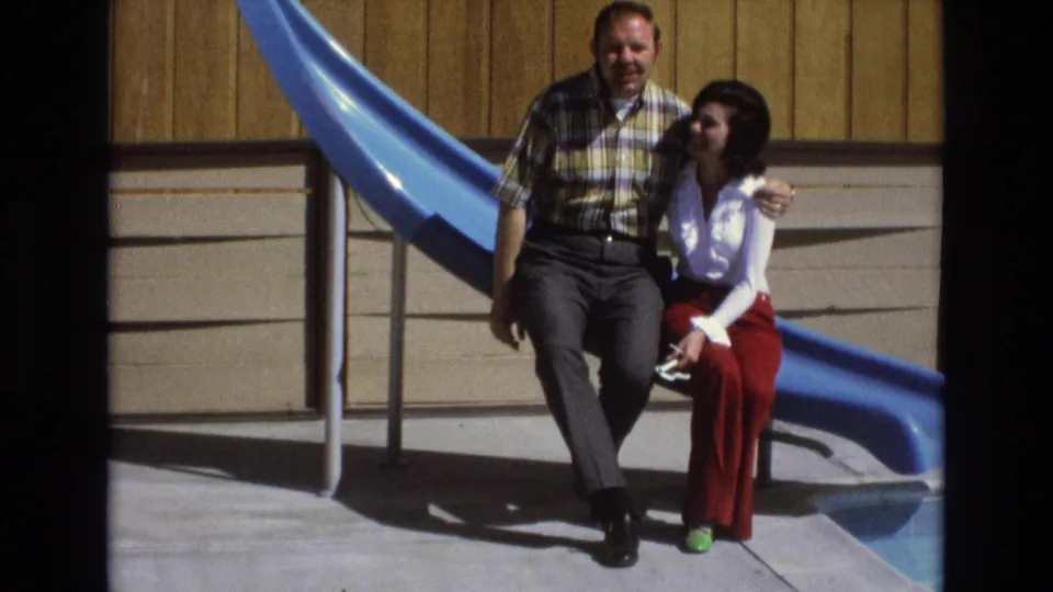Near the end of the 1973 Central Coast California clip, the woman turns toward the man as they sit arm in arm on the bright blue slide.