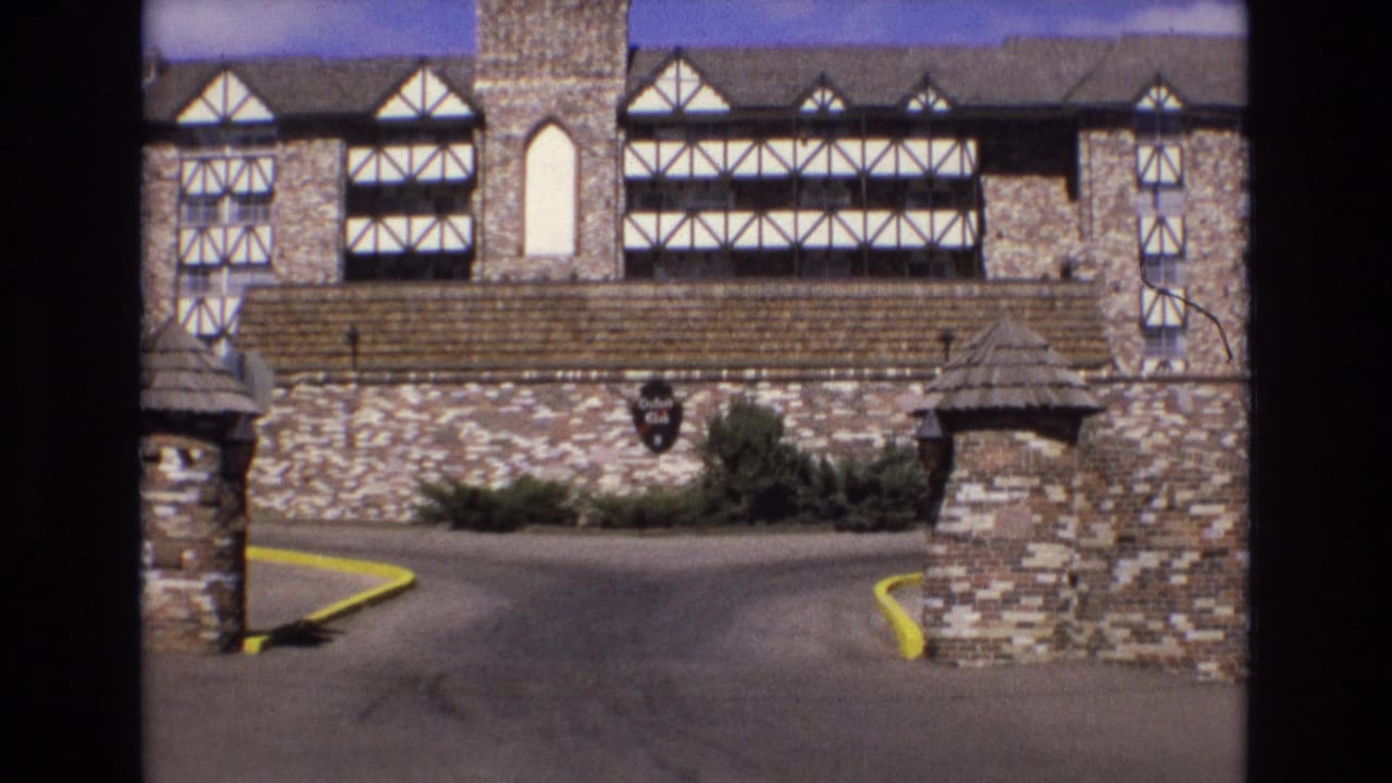 Tudor-style stone building behind a private driveway and brick gateposts.