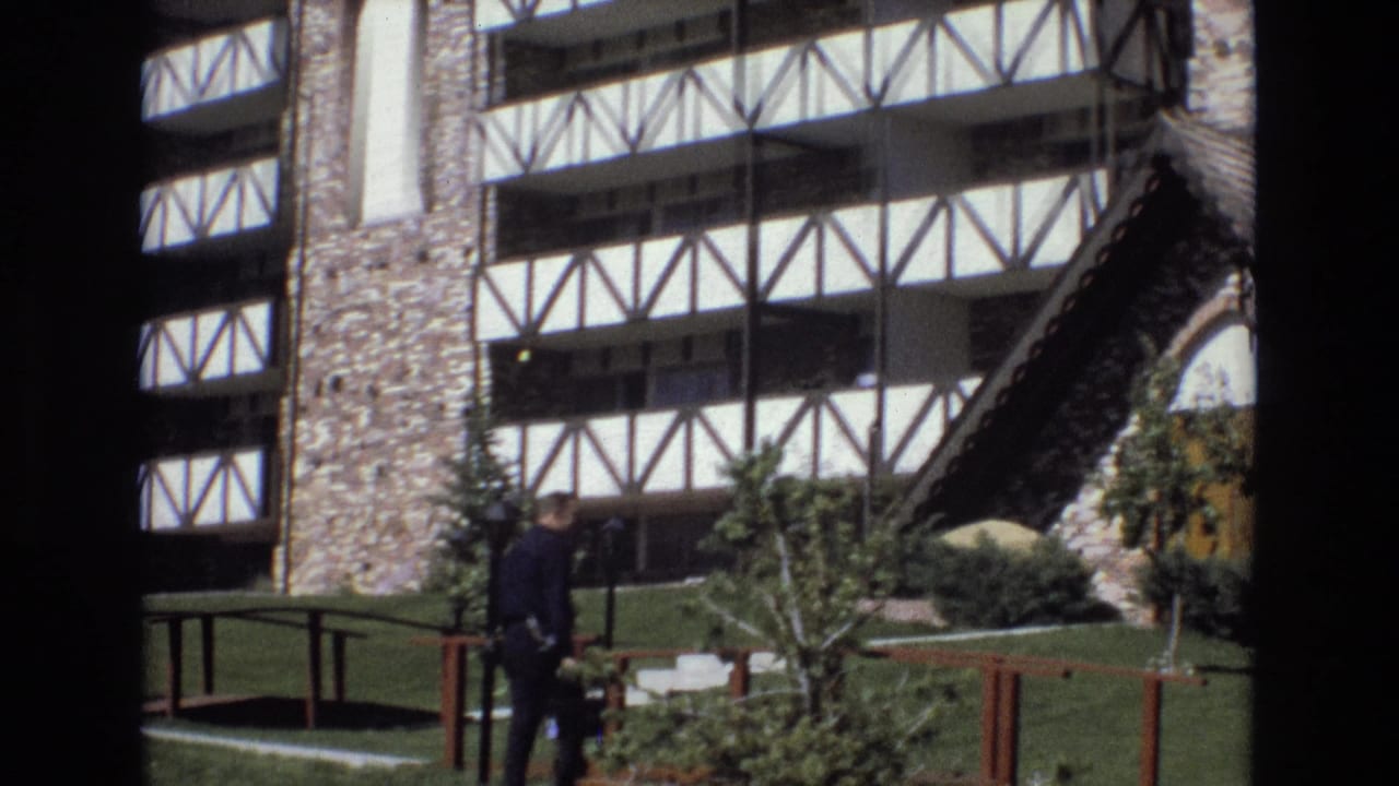 Man continues walking past railings and landscaping toward the building.