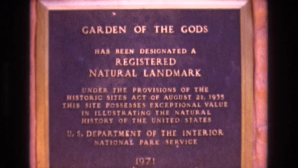 1973 Colorado home-movie frame showing a brass Garden of the Gods Registered Natural Landmark plaque issued by the U.S. Department of the Interior National Park Service.