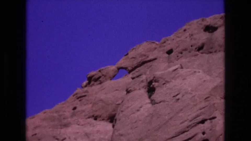 Colorado home-movie frame from 1973 showing the Garden of the Gods rock formation with a small natural arch and textured sandstone surface.