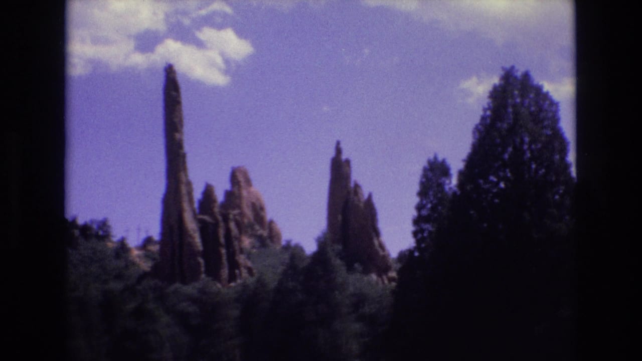 Rock pinnacles stand above treetops with a large dark tree mass at the right edge.