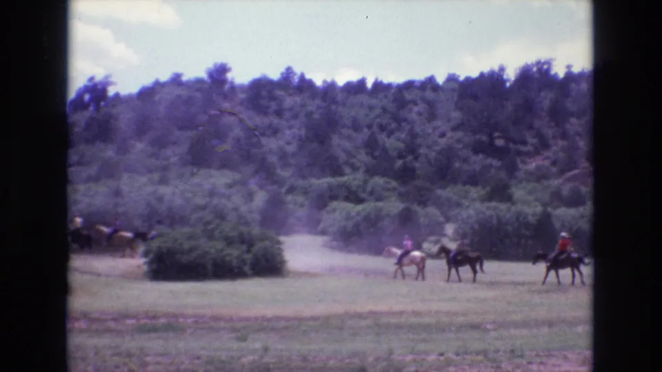 By the end of the 1973 Colorado clip, riders on horses are spread across the field, with dust, shrubs, trees, and visible 8mm frame borders in view.