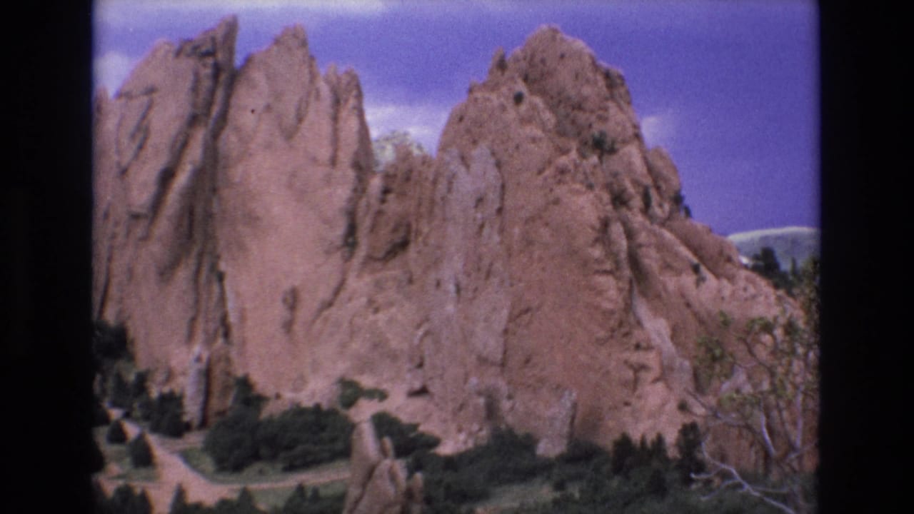 Red rock fins fill the frame with vegetation below and sky above.