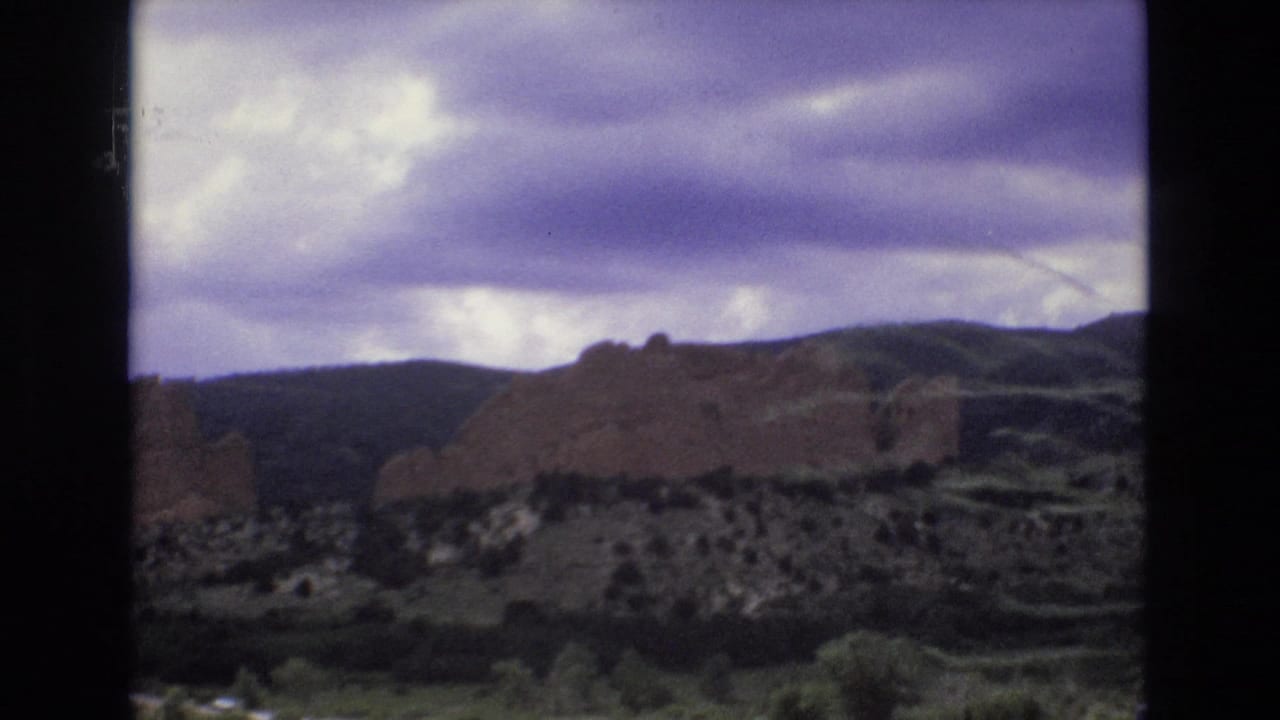 Red rock formations below a cloudy purple-tinged sky.