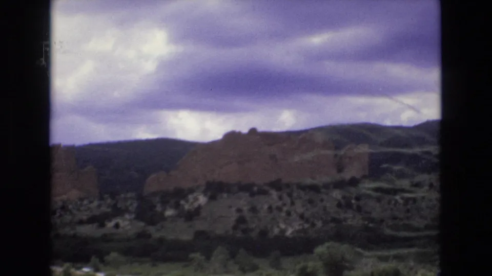 Colorado red rock formations, consistent with Garden of the Gods metadata, seen under a dramatic purple-tinged sky in 1970s 8mm home-movie footage.