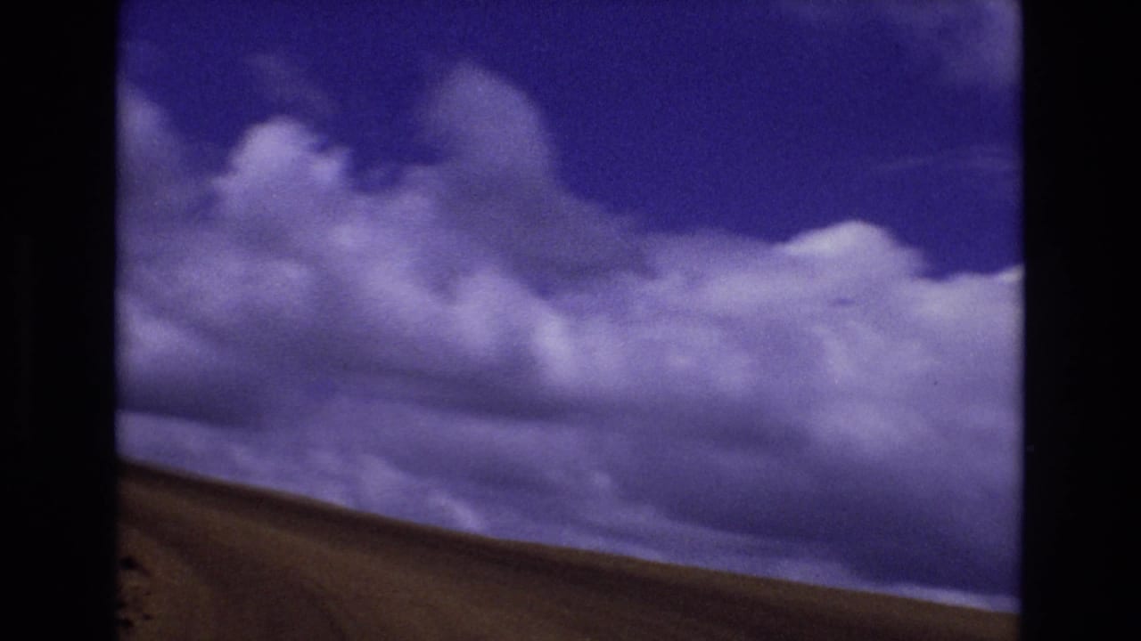Purple-tinted clouds above a sloping rural hillside.
