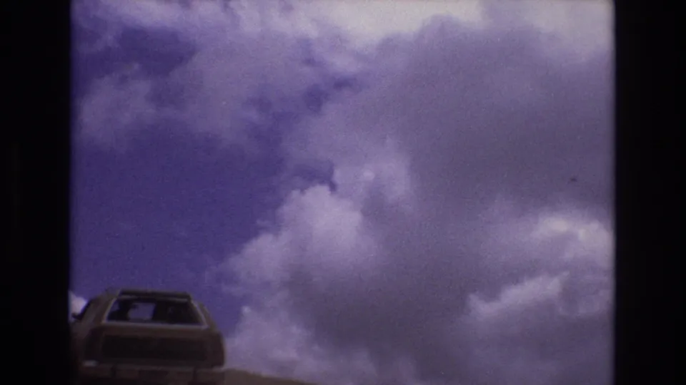 1973 Colorado 8mm frame with a boxy car low in the composition and broad cloud cover filling the sky.