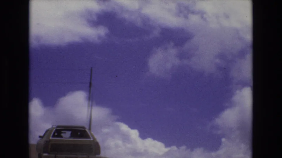 The station wagon remains low in the frame as a utility pole passes beside it against the clouded 1973 Colorado sky.